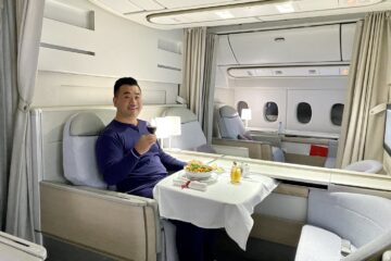 a man sitting in a chair with a plate of food and a glass of wine