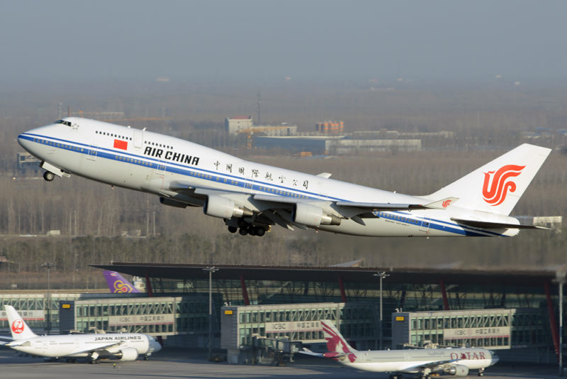 a white airplane flying over a runway