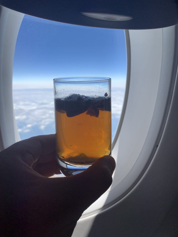 a hand holding a glass of brown liquid