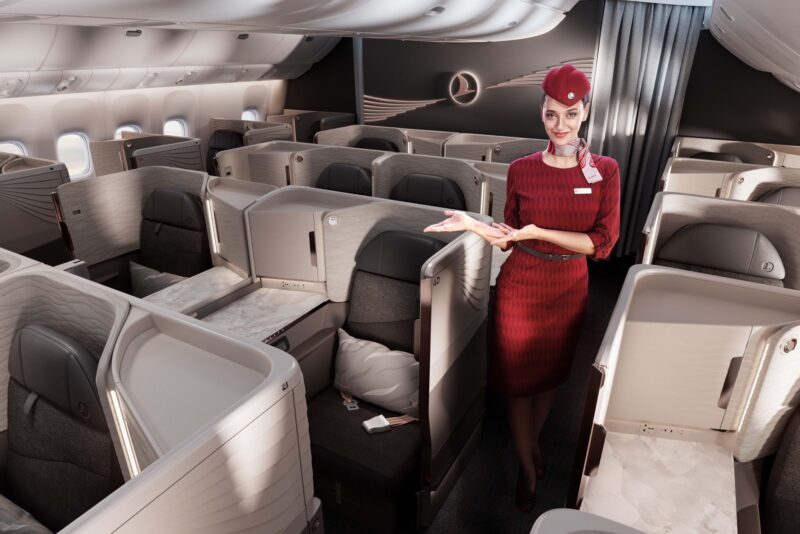 a woman in a red dress and hat standing in an airplane