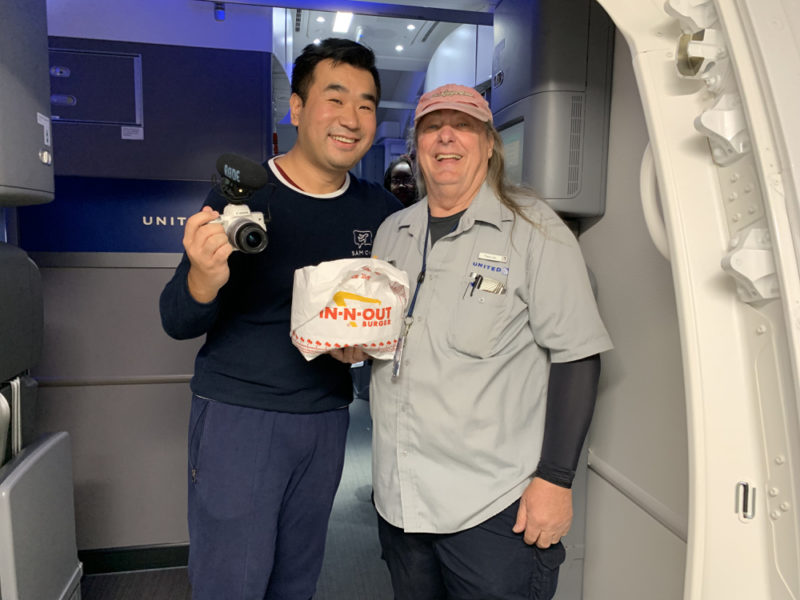 a man holding a camera next to a man standing in a room